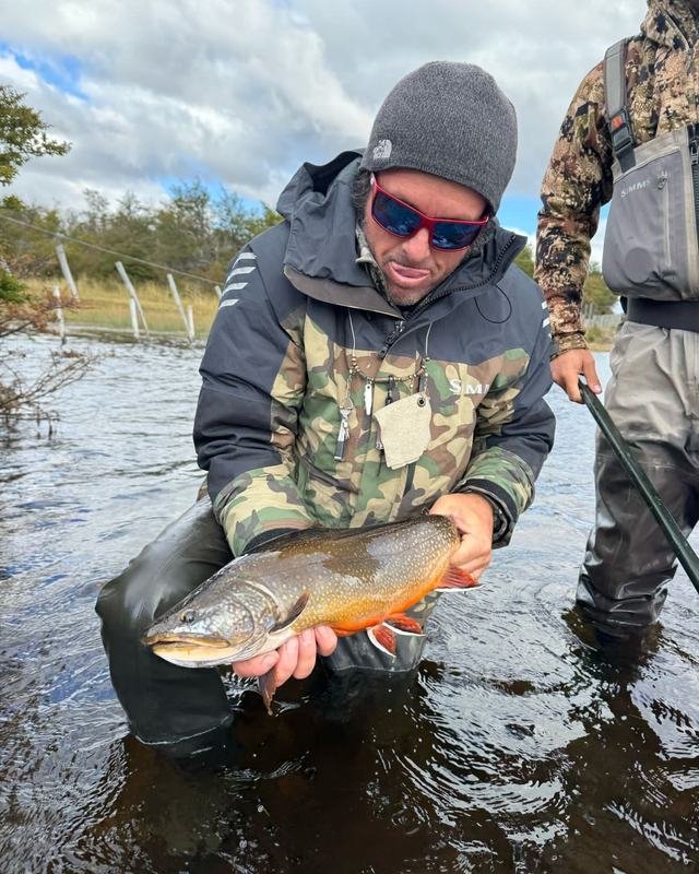 An angler holding a brook trout in a Patagonian river